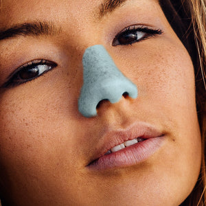 Young person with freckles wearing Noz light blue sunscreen on nose